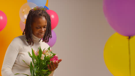 Studioporträt-Einer-Frau-Mit-Geburtstagsstirnband,-Die-Einen-Blumenstrauß-Hält-Und-Mit-Luftballons-Feiert-2